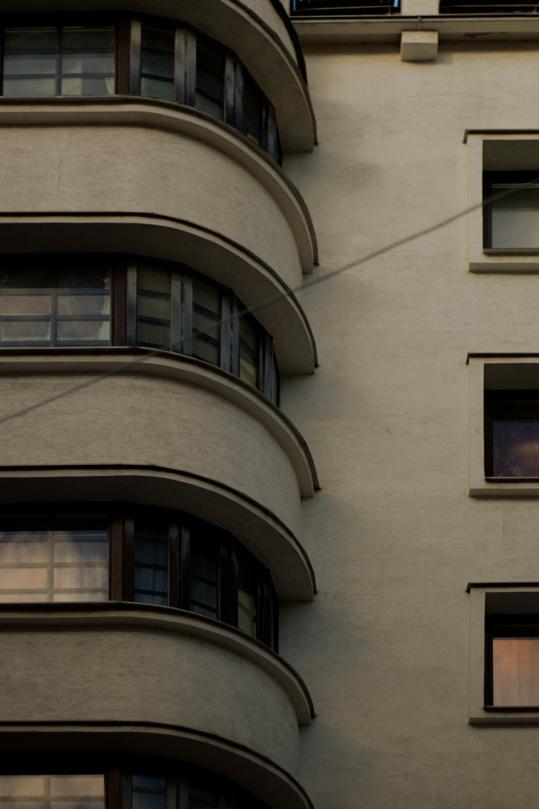 Zaokrąglone balkony przedwojennej kamienicy modernistycznej w świetle zachodzącego słońca
